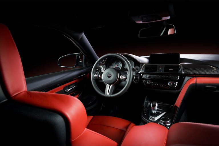 Donker auto-interieur met rode leren stoelen, stuur en middenconsole